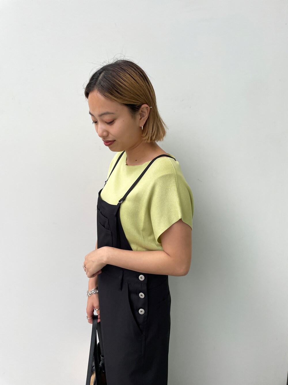 グリーン系のニット/セーター、ブラック系のサロペット/オーバーオール、ブラック系のトートバッグを着用したレディースの夏コーディネートの3枚目の写真