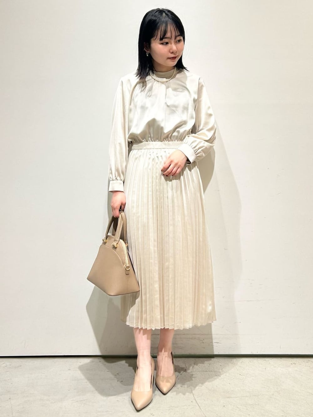 ホワイト系のノーカラージャケット、ベージュ系のワンピース、ベージュ系のトートバッグを着用したレディースの冬コーディネートの3枚目の写真