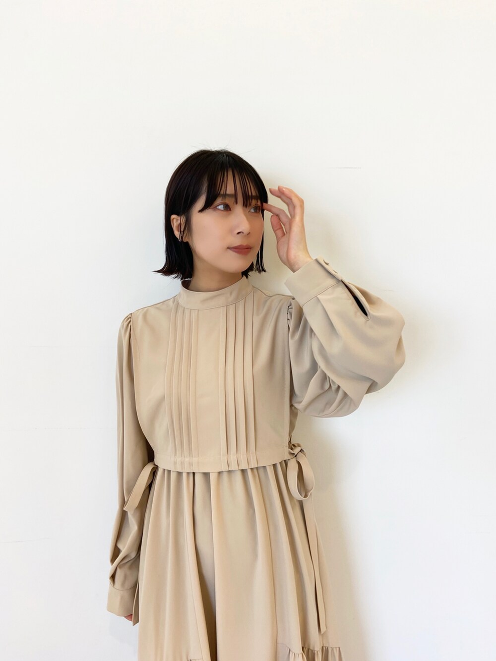 ベージュ系のワンピース、ホワイト系のブーツを着用したレディースの冬コーディネートの2枚目の写真