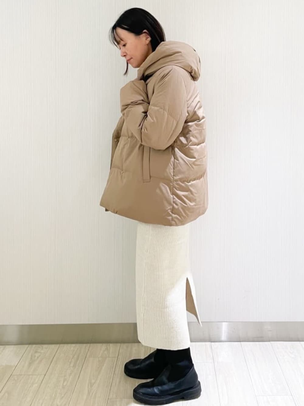 ホワイト系のスカート、ホワイト系のニット/セーター、イエロー系のダウンジャケット/コートを着用したレディースの秋コーディネートの2枚目の写真