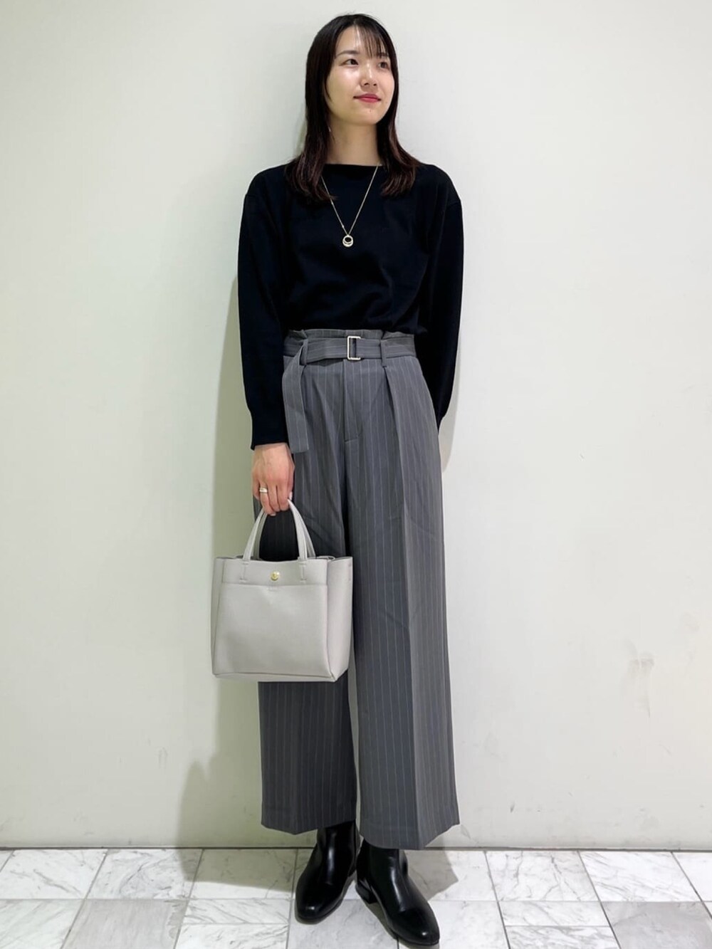 ブラック系のニット/セーター、ホワイト系のノーカラーコート、グレー系のその他パンツを着用したレディースの冬コーディネートの4枚目の写真