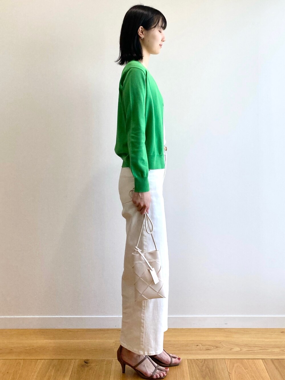 ブラック系のサンダル、ホワイト系のショルダーバッグ、ホワイト系のデニムパンツを着用したレディースの春コーディネートの2枚目の写真