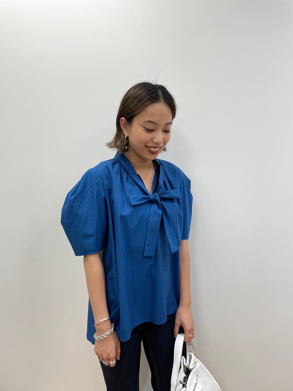 ブルー系のシャツ/ブラウス、ブルー系のデニムパンツ、ホワイト系のショルダーバッグを着用したレディースの夏コーディネートの4枚目の写真