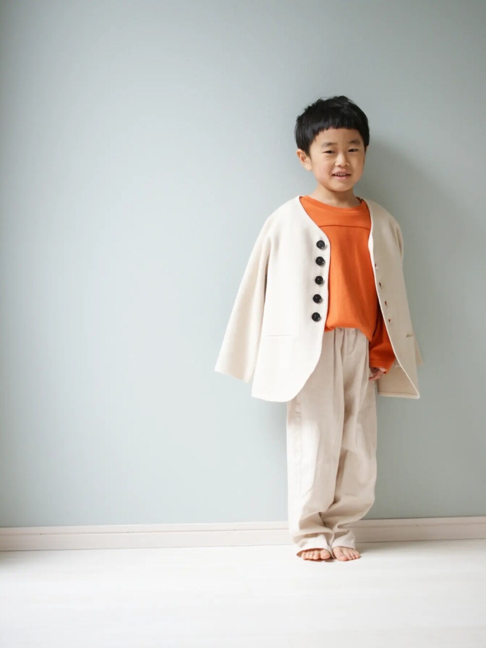 ホワイト系のパンツ、オレンジ系のTシャツ/カットソー、ホワイト系のニット/セーターを着用したキッズの春コーディネートの2枚目の写真