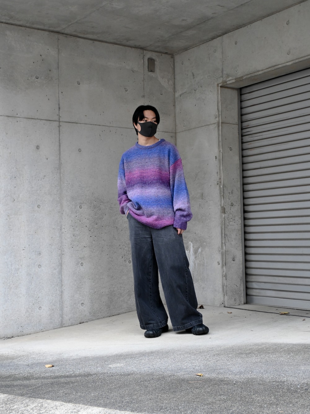 ブラック系のデニムパンツ、パープル系のニット/セーター、ブラック系のスニーカーを着用したメンズの秋コーディネートの2枚目の写真
