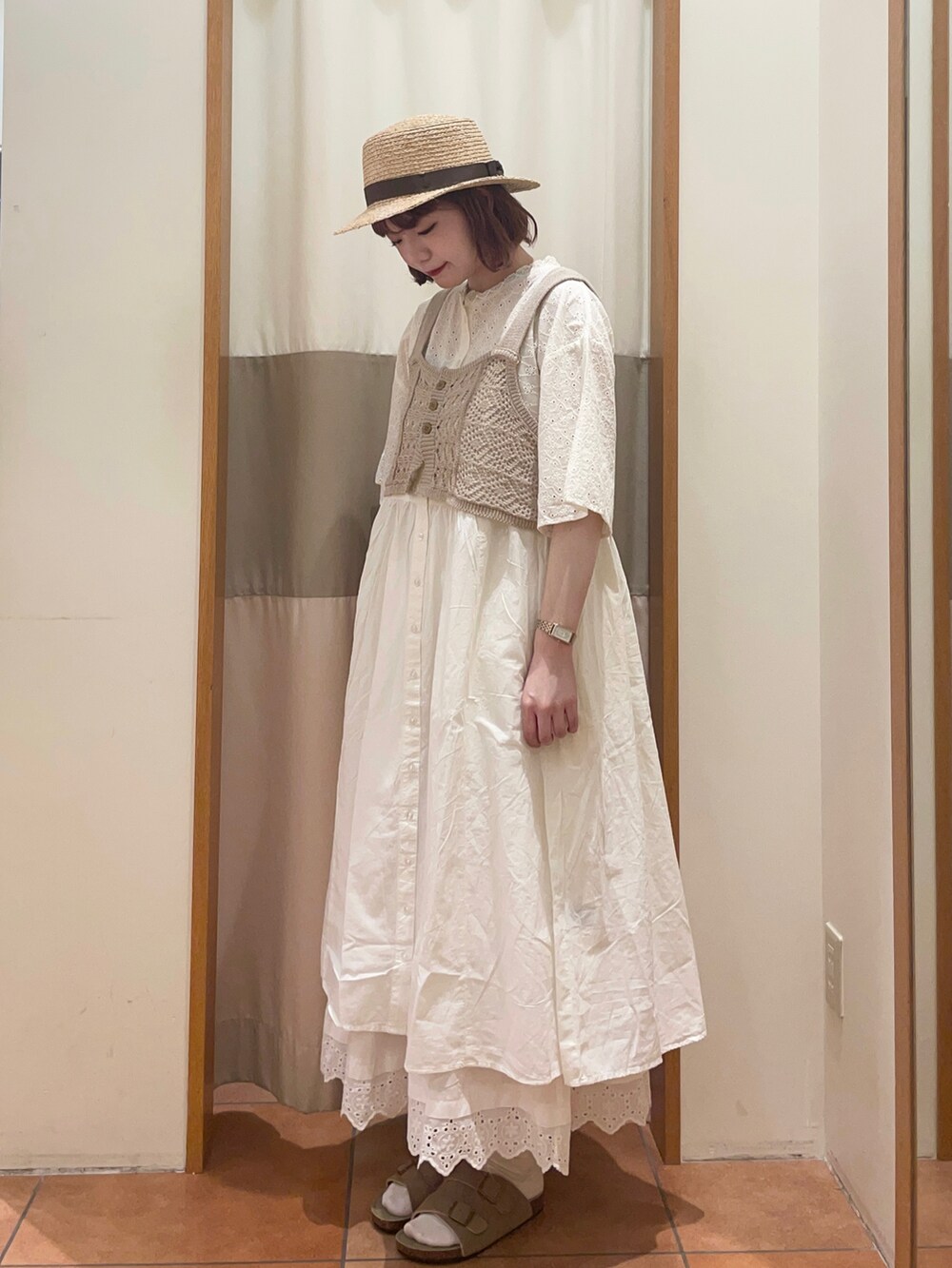 ホワイト系のワンピース、ホワイト系のスカート、ベージュ系のベストを着用したレディースの春コーディネートの2枚目の写真
