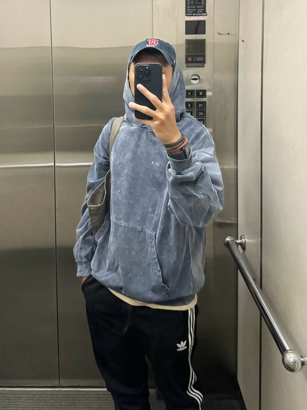 ブルー系のジャージ、ブラック系のチノパンツ、ブラウン系のトートバッグを着用したメンズの春コーディネートの2枚目の写真