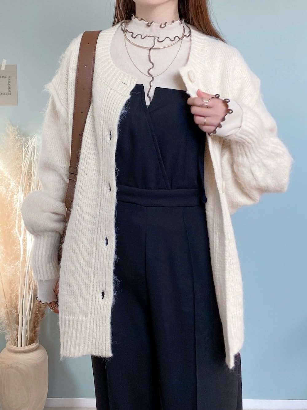 ブラック系のつなぎ/オールインワン、ベージュ系のカーディガン/ボレロ、ブラウン系のバッグを着用したレディースの冬コーディネートの2枚目の写真