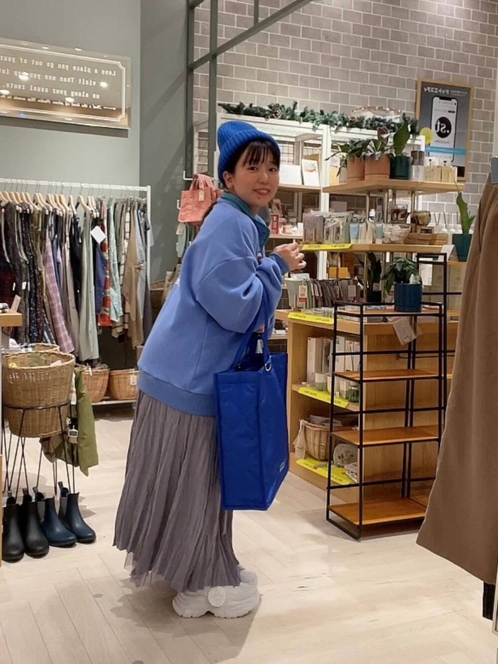 ブルー系のショルダーバッグ、パープル系のスカート、ホワイト系のスニーカーを着用したレディースの冬コーディネートの8枚目の写真