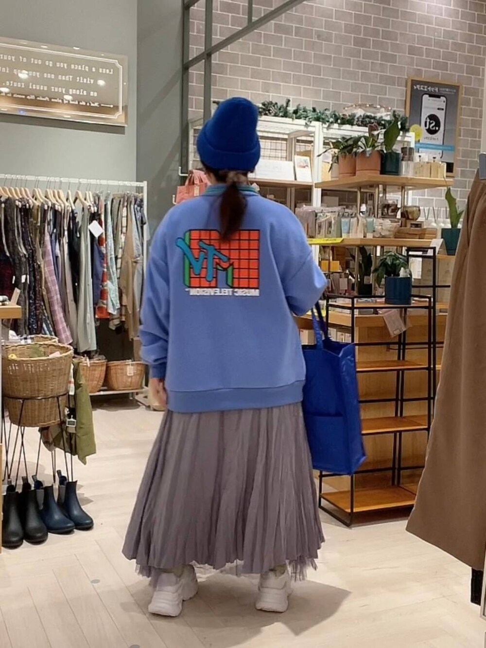 ブルー系のショルダーバッグ、パープル系のスカート、ホワイト系のスニーカーを着用したレディースの冬コーディネートの6枚目の写真