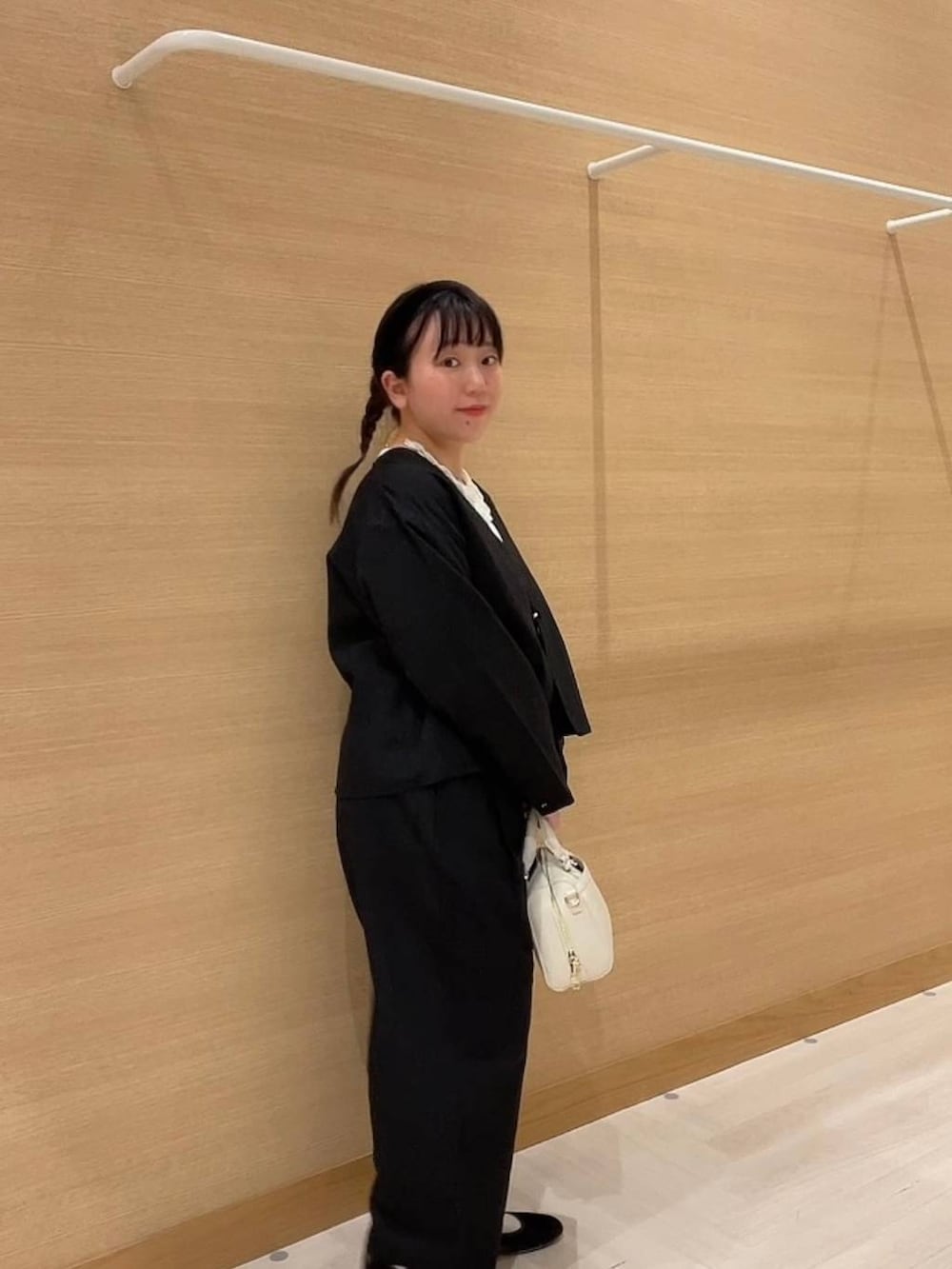 グリーン系のパンプス、ホワイト系のショルダーバッグ、ブラック系のノーカラージャケットを着用したレディースの冬コーディネートの2枚目の写真