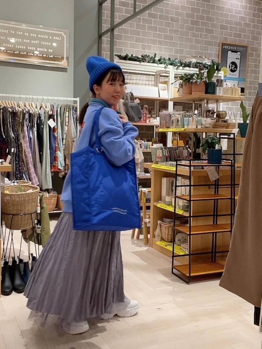 ブルー系のショルダーバッグ、パープル系のスカート、ホワイト系のスニーカーを着用したレディースの冬コーディネートの9枚目の写真