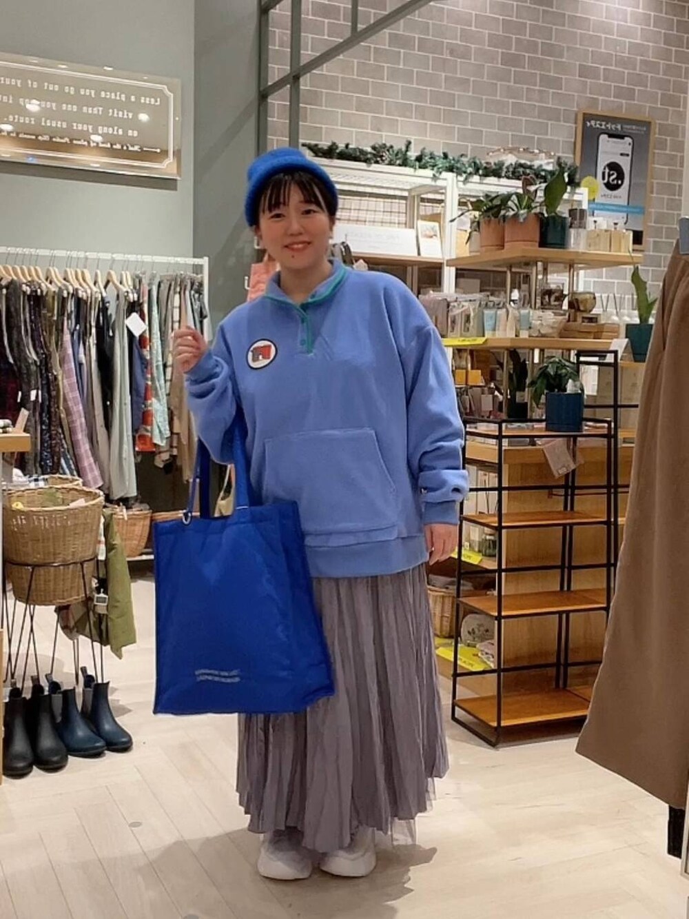 ブルー系のショルダーバッグ、パープル系のスカート、ホワイト系のスニーカーを着用したレディースの冬コーディネートの5枚目の写真