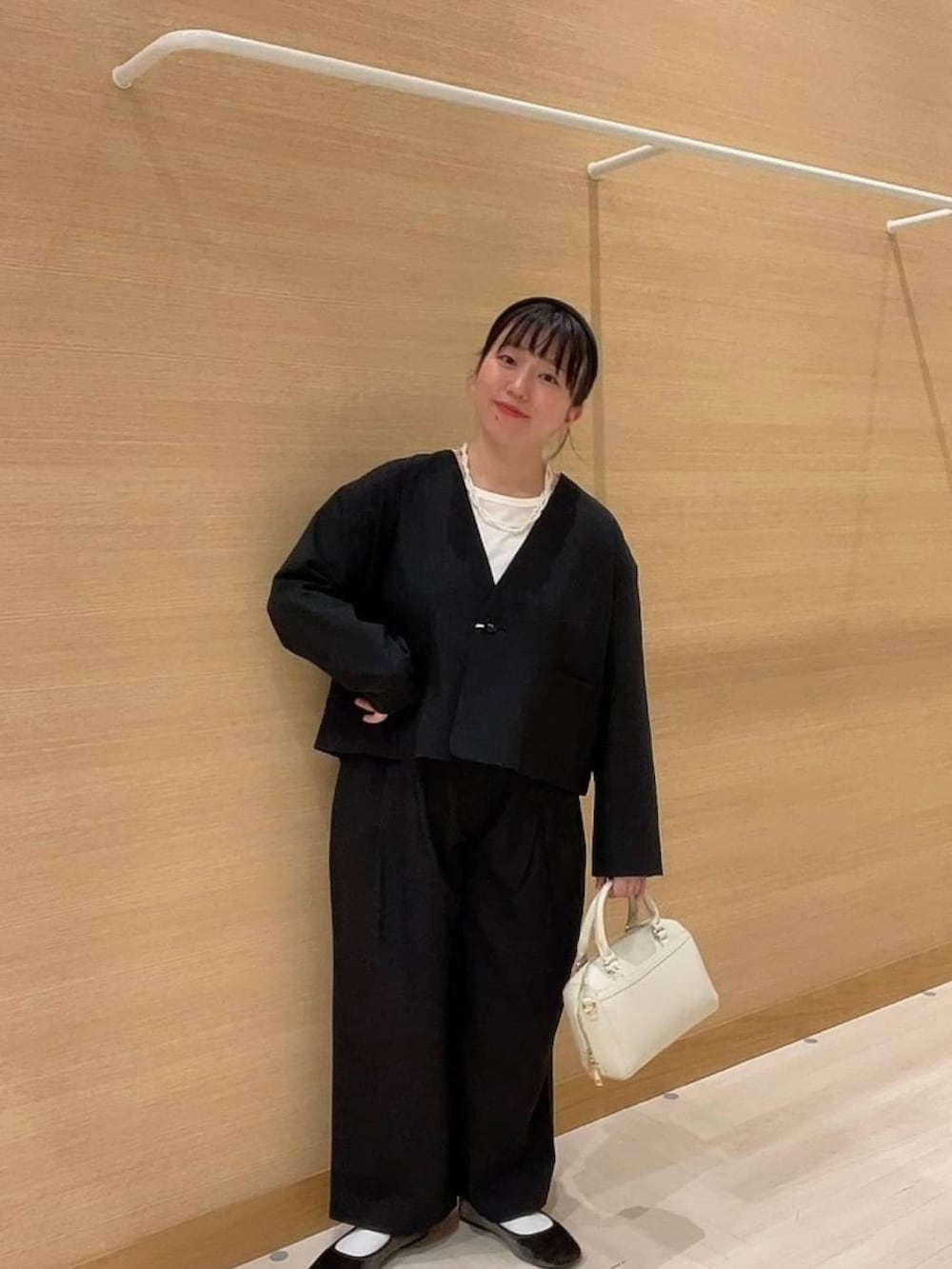 グリーン系のパンプス、ホワイト系のショルダーバッグ、ブラック系のノーカラージャケットを着用したレディースの冬コーディネートの3枚目の写真