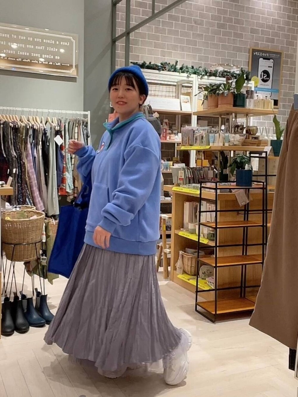 ブルー系のショルダーバッグ、パープル系のスカート、ホワイト系のスニーカーを着用したレディースの冬コーディネートの2枚目の写真