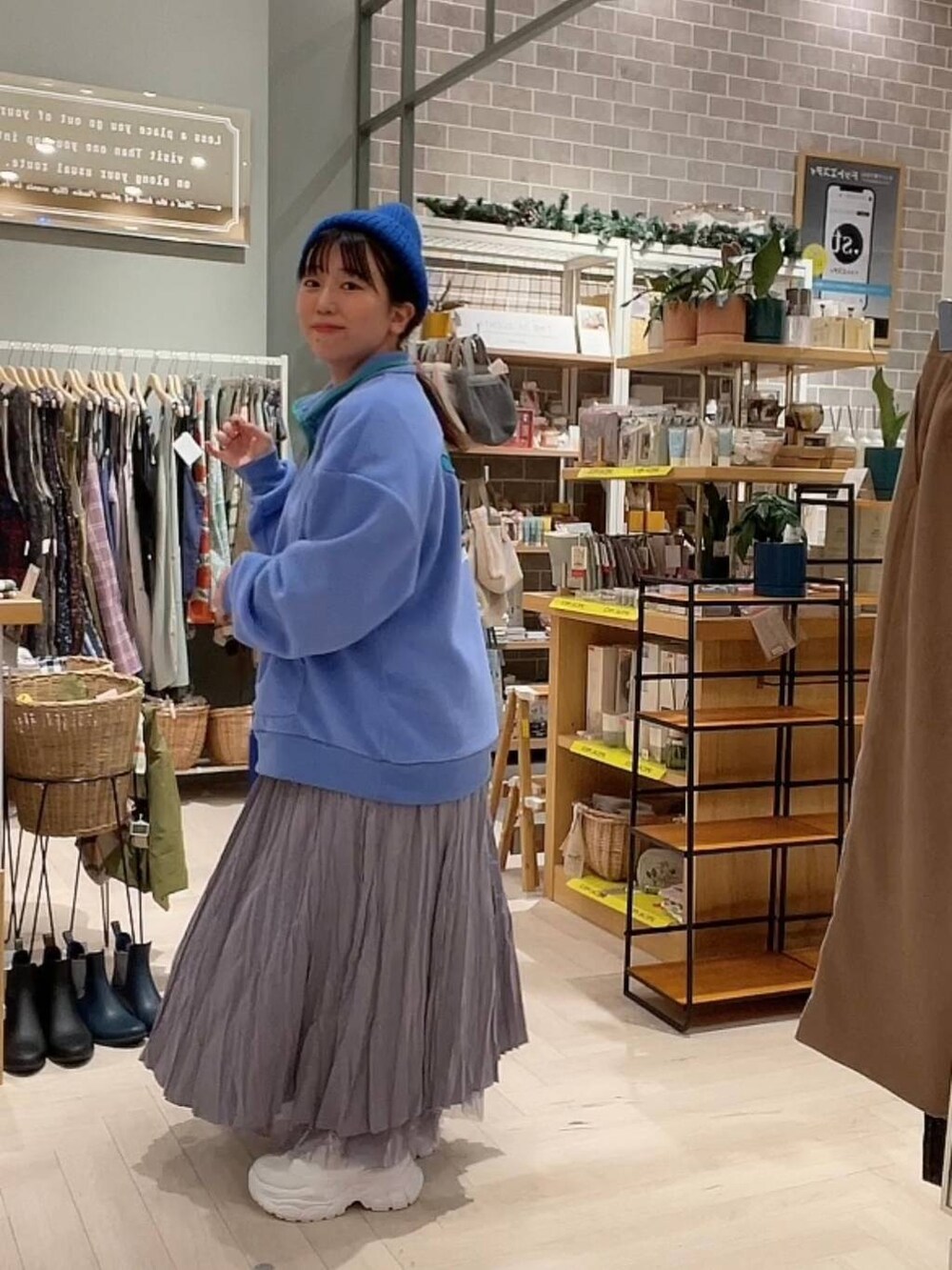 ブルー系のショルダーバッグ、パープル系のスカート、ホワイト系のスニーカーを着用したレディースの冬コーディネートの7枚目の写真