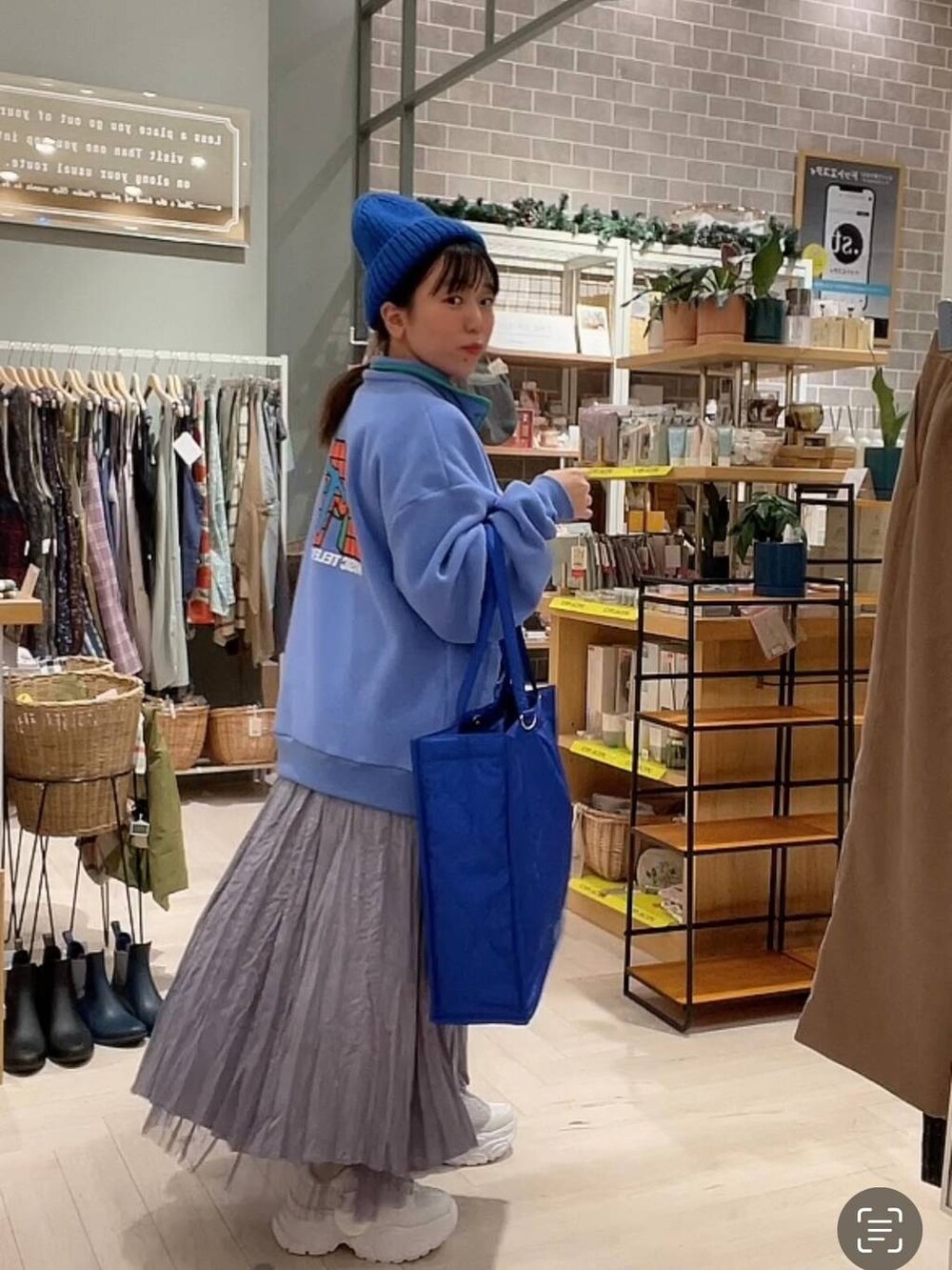 ブルー系のショルダーバッグ、パープル系のスカート、ホワイト系のスニーカーを着用したレディースの冬コーディネートの3枚目の写真