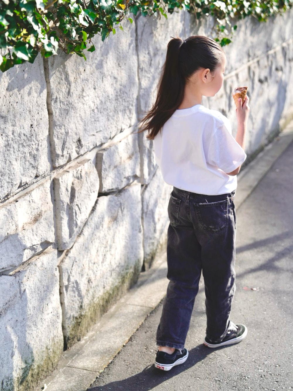 ブラック系のデニムパンツ、ブラック系のスニーカー、ホワイト系のTシャツ/カットソーを着用したキッズの春コーディネートの5枚目の写真