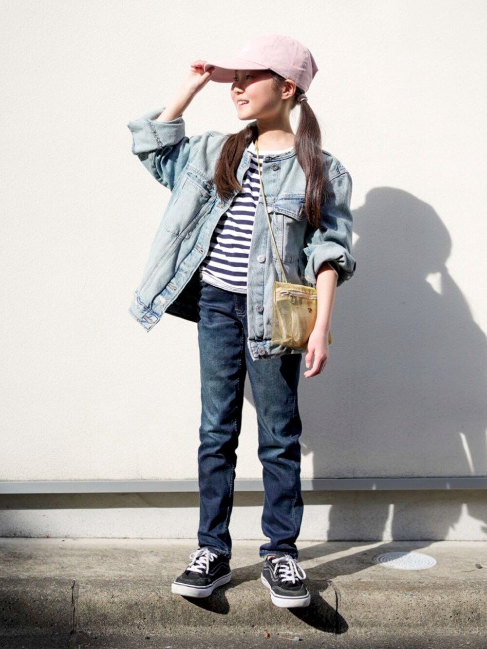 ブルー系のデニムパンツ、ブルー系のデニムジャケット、ゴールド系のショルダーバッグを着用したキッズの春コーディネートの2枚目の写真