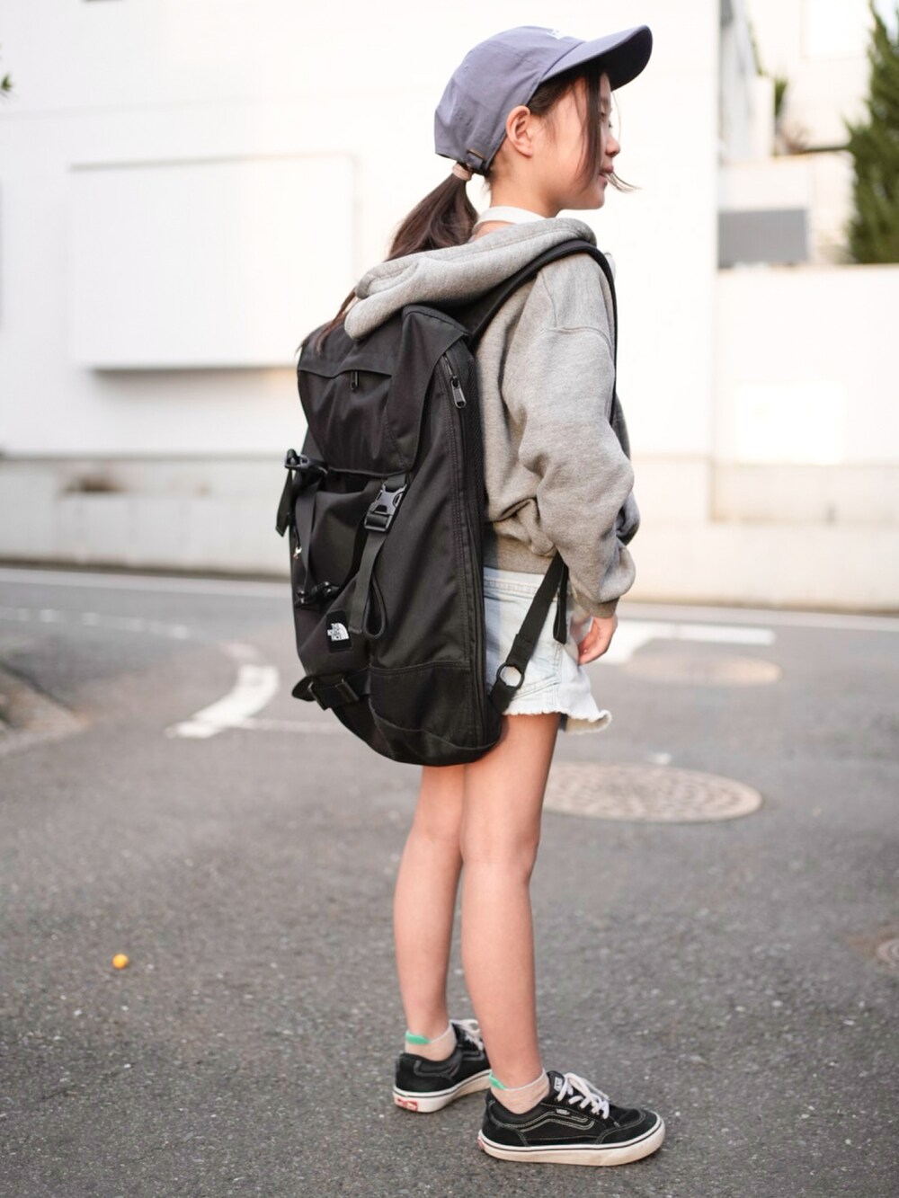 ブラック系のバックパック/リュック、ブラック系のスニーカー、グレー系のパーカーを着用したキッズの春コーディネートの2枚目の写真