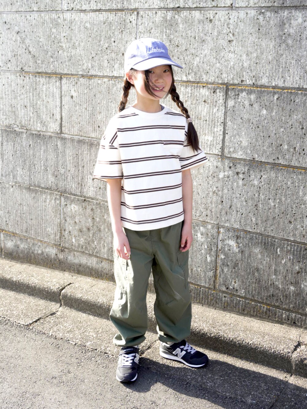 グリーン系のパンツ、ホワイト系のTシャツ/カットソー、ブラック系のスニーカーを着用したキッズの春コーディネートの2枚目の写真