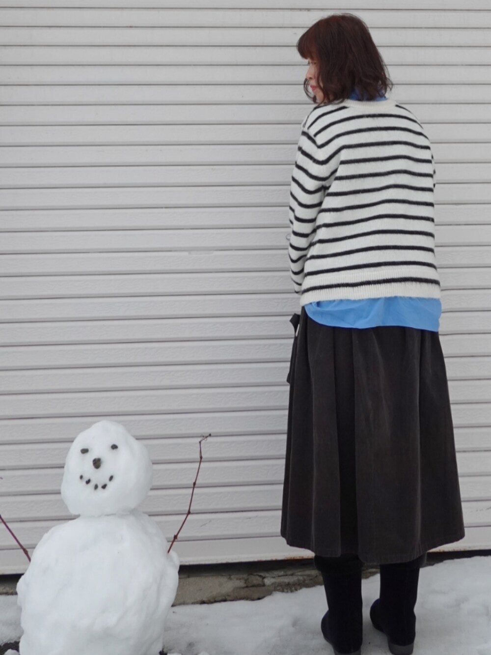 ホワイト系のカーディガン/ボレロ、グレー系のスカート、ブルー系のシャツ/ブラウスを着用したレディースの冬コーディネートの2枚目の写真