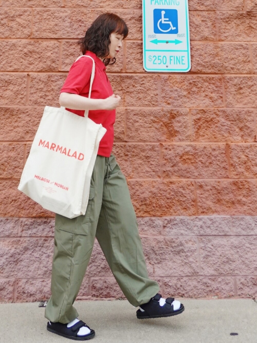 ベージュ系のトートバッグ、グリーン系のカーゴパンツ、ブラック系のサンダルを着用したレディースの夏コーディネートの2枚目の写真