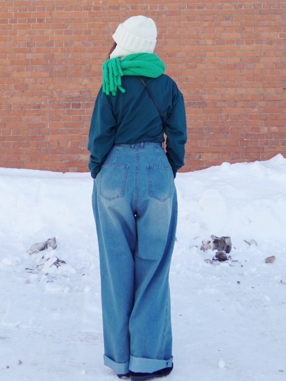 グリーン系のスウェット、ブラック系のショルダーバッグ、ブルー系のデニムパンツを着用したレディースの冬コーディネートの4枚目の写真