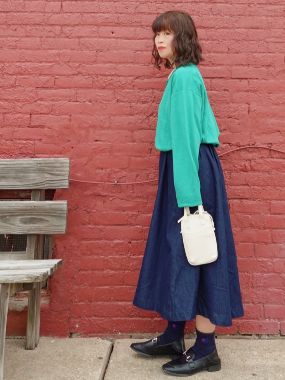 グリーン系のカーディガン/ボレロ、ブラック系のローファー、ブルー系のデニムスカートを着用したレディースの秋コーディネートの2枚目の写真