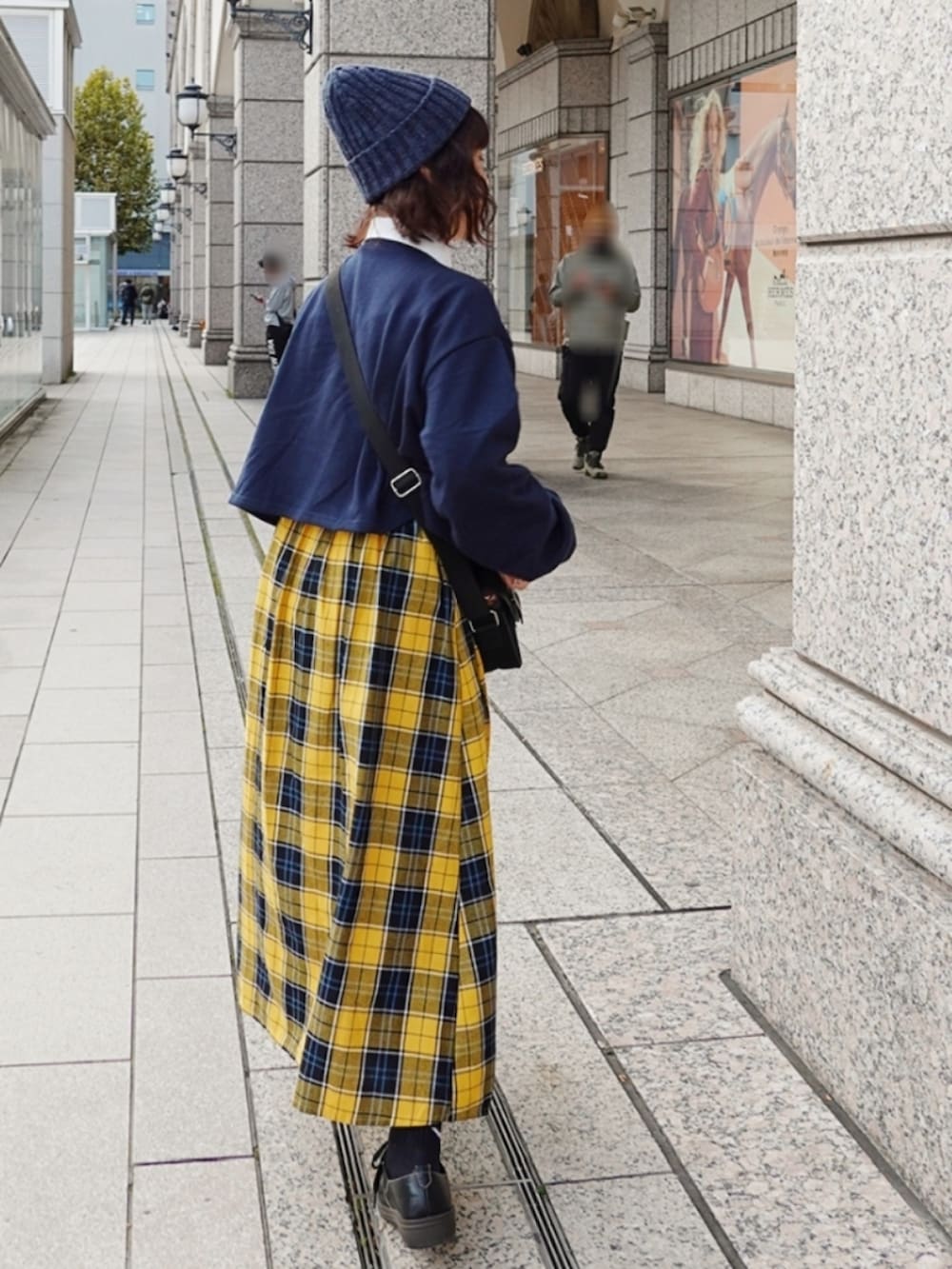 ブラック系のスニーカー、イエロー系のスカート、ブラック系のショルダーバッグを着用したレディースの秋コーディネートの2枚目の写真