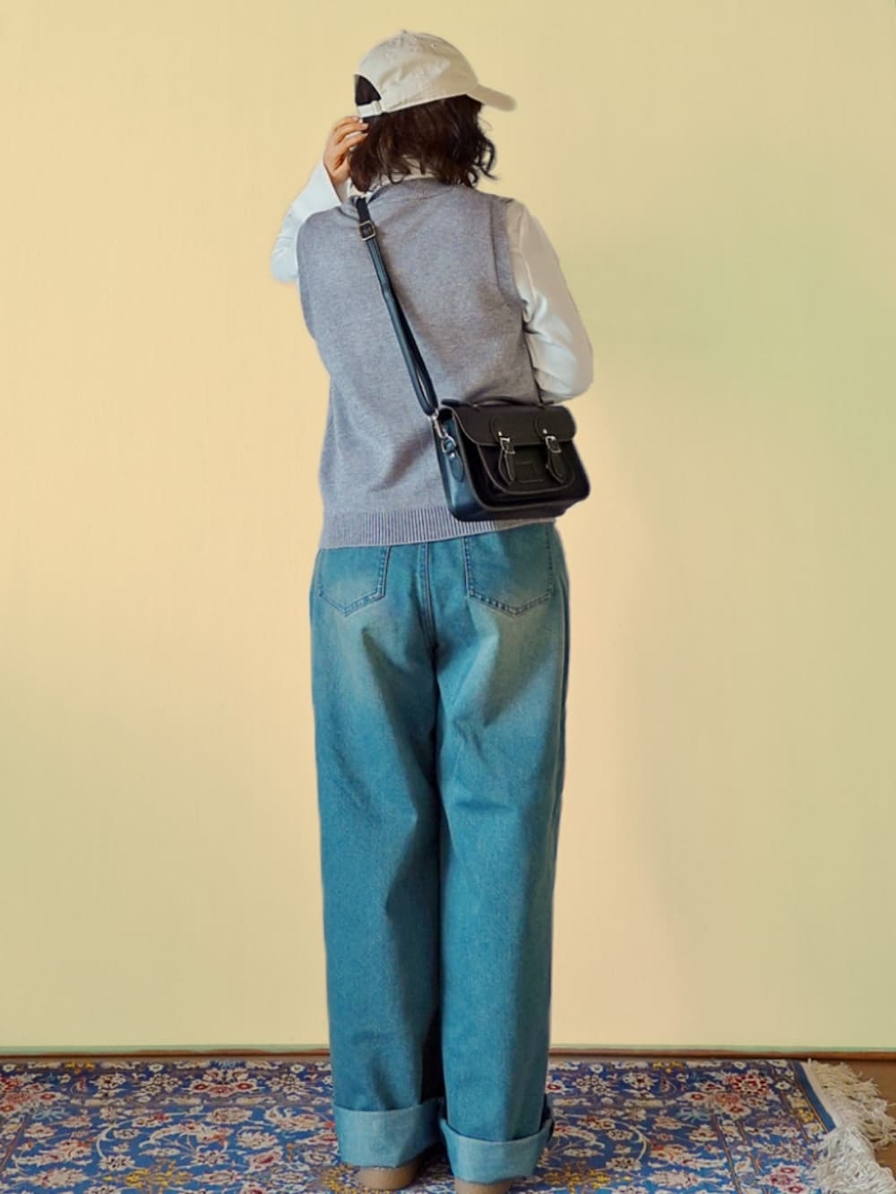 グレー系のベスト、ブルー系のデニムパンツ、ブラック系のショルダーバッグを着用したレディースの冬コーディネートの3枚目の写真