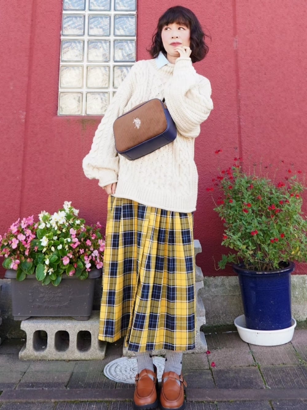 ブラウン系のショルダーバッグ、イエロー系のスカート、イエロー系のローファーを着用したレディースの秋コーディネートの2枚目の写真