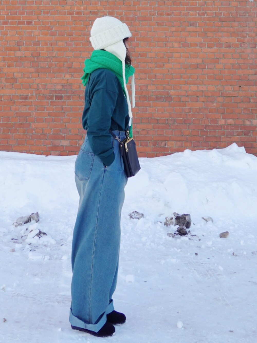 グリーン系のスウェット、ブラック系のショルダーバッグ、ブルー系のデニムパンツを着用したレディースの冬コーディネートの3枚目の写真