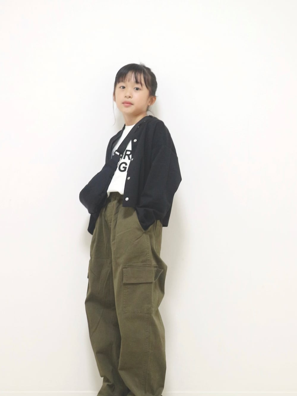 ブラック系のニット/セーター、ホワイト系のTシャツ/カットソー、グリーン系のカーゴパンツを着用したキッズの秋コーディネートの2枚目の写真