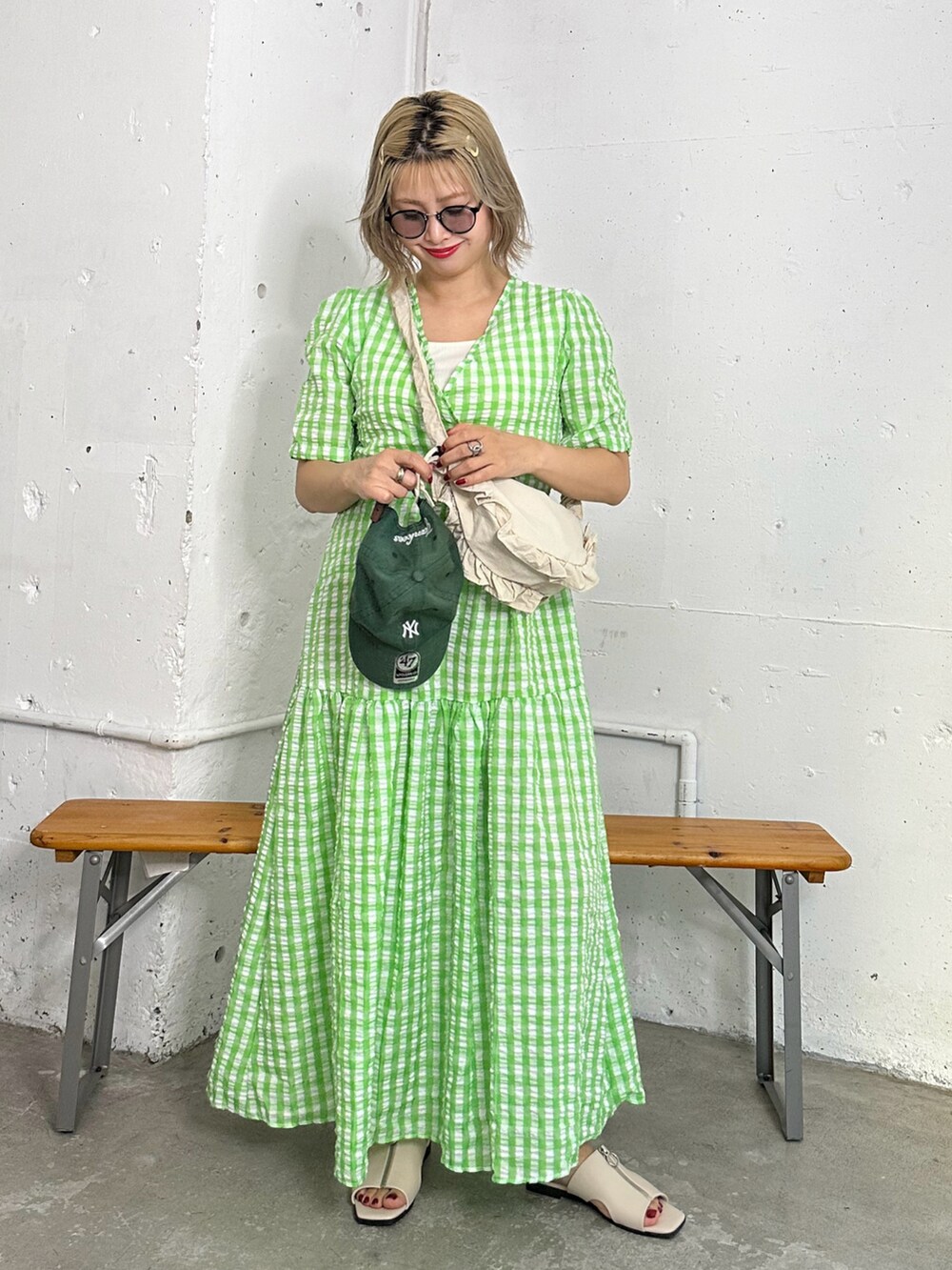 グリーン系のワンピース、ホワイト系のサンダル、グリーン系のキャップを着用したレディースの夏コーディネートの2枚目の写真