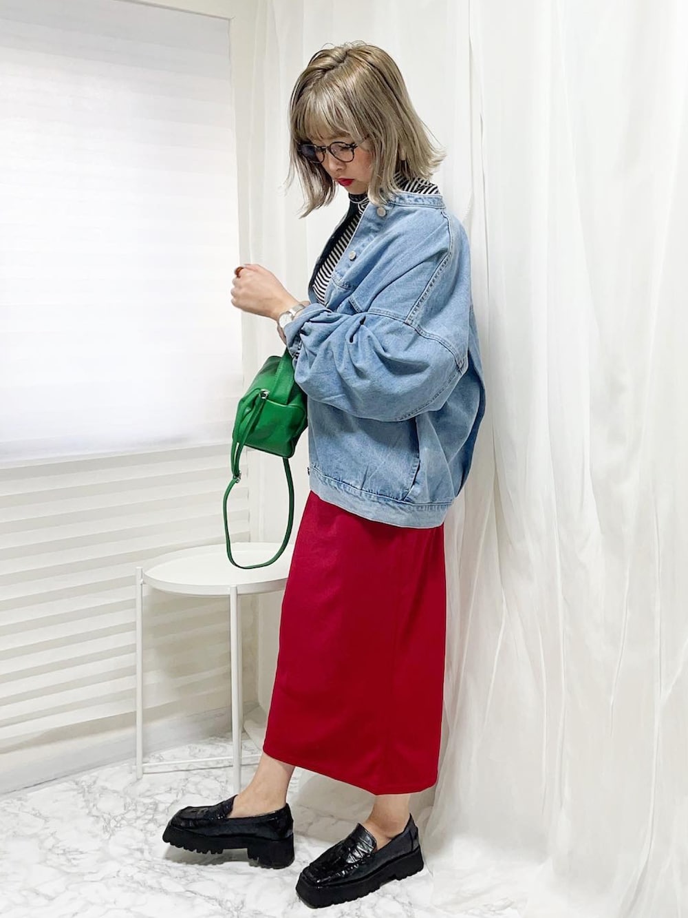 グリーン系のバッグ、レッド系のスカート、ブラック系のトップスを着用したレディースの春コーディネートの3枚目の写真