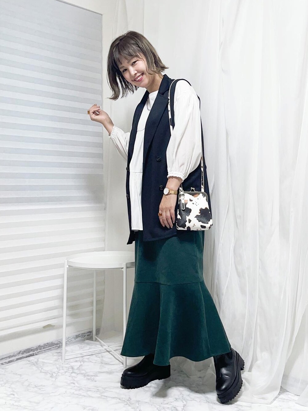 ブラック系のベスト、ホワイト系のショルダーバッグ、ホワイト系のチュニックを着用したレディースの秋コーディネートの2枚目の写真