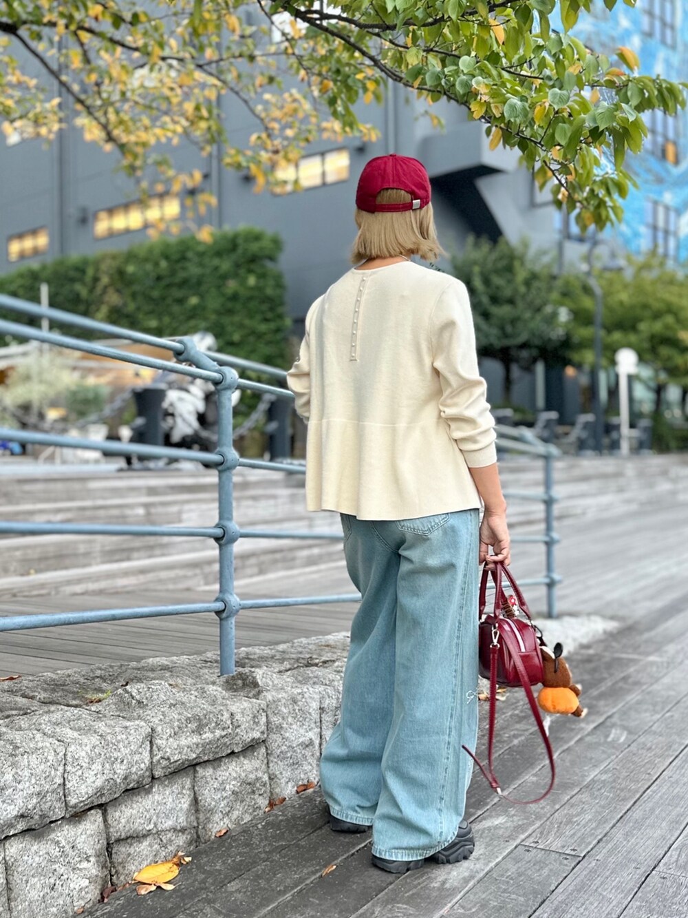 ホワイト系のニット/セーター、ブラック系のスニーカー、ブルー系のデニムパンツを着用したレディースの秋コーディネートの3枚目の写真