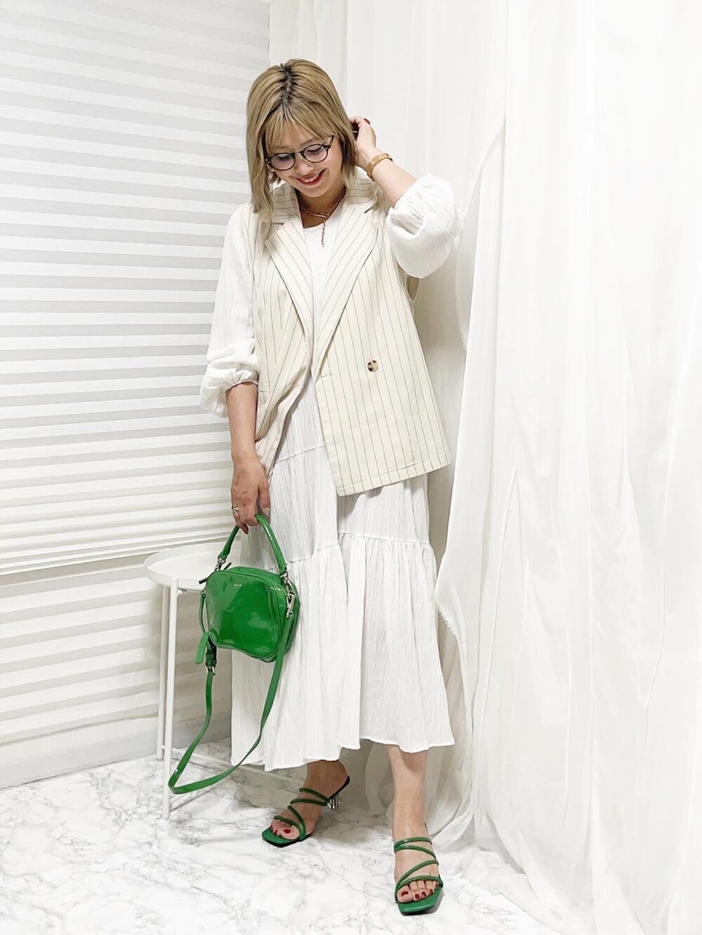 ホワイト系のベスト、グリーン系のショルダーバッグ、ホワイト系のワンピースを着用したレディースの春コーディネートの3枚目の写真