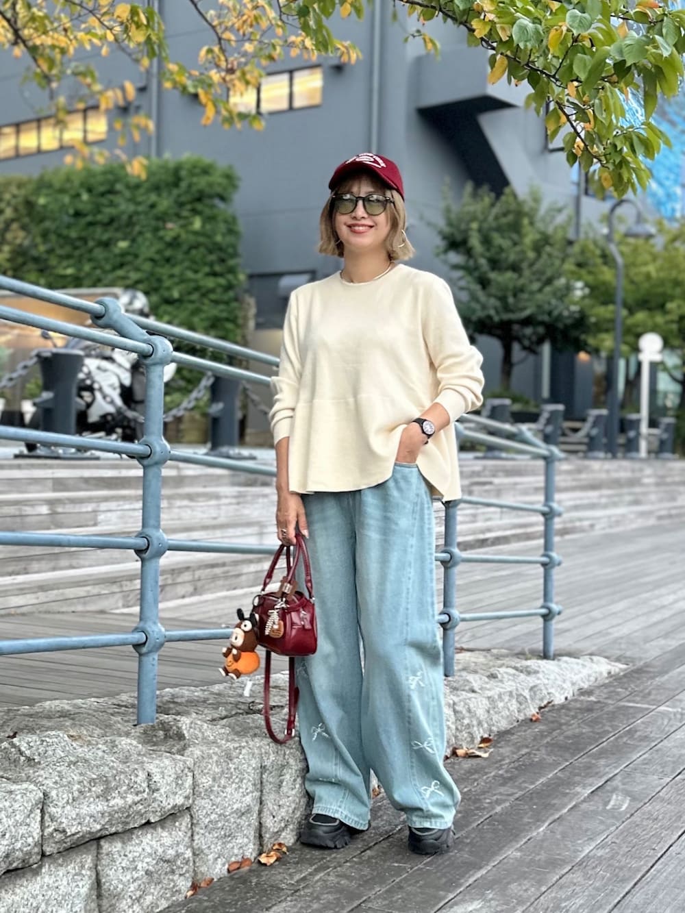 ホワイト系のニット/セーター、ブラック系のスニーカー、ブルー系のデニムパンツを着用したレディースの秋コーディネートの2枚目の写真