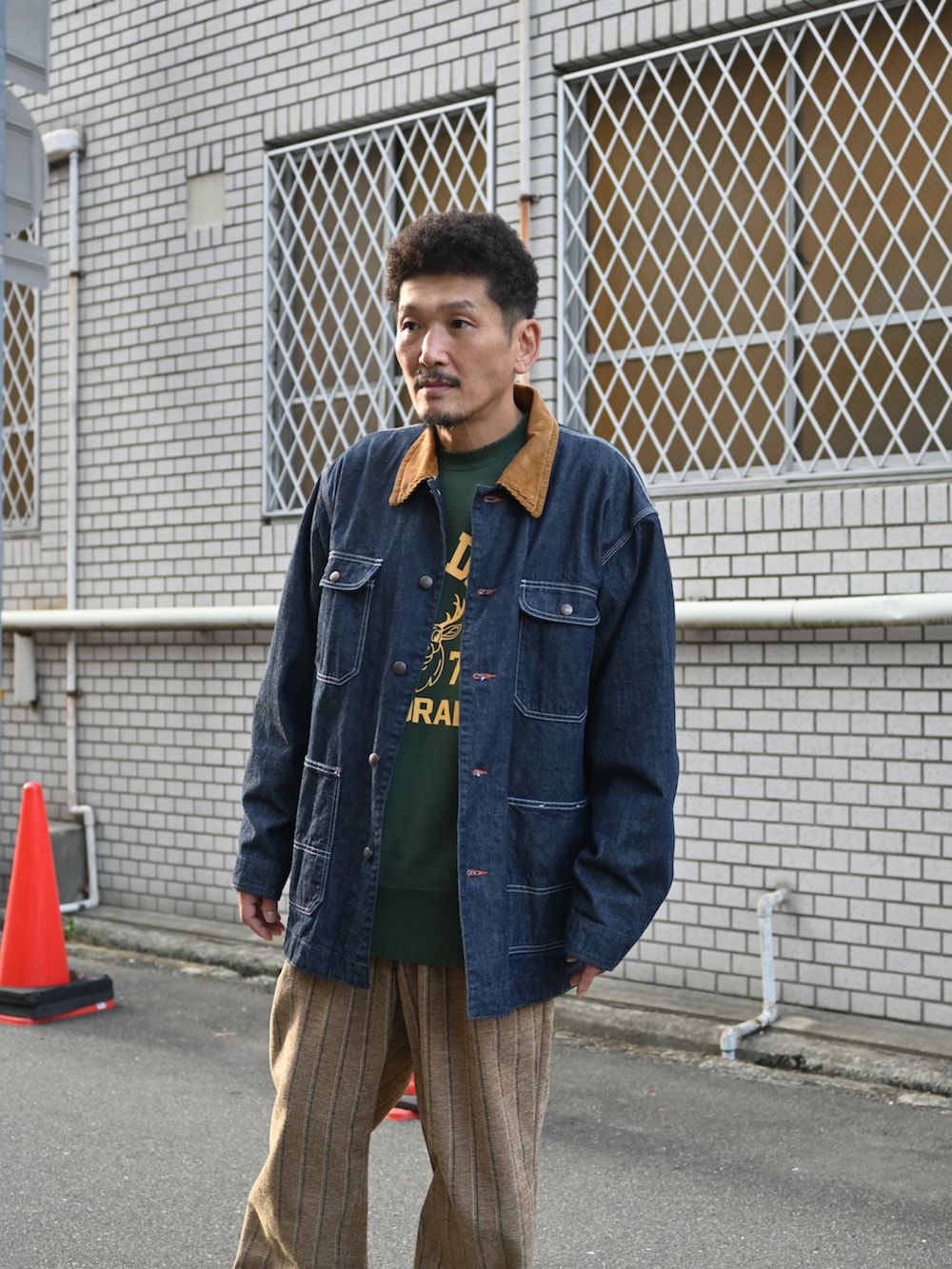 グリーン系のスウェット、ブルー系のデニムジャケット、ブラウン系のその他パンツを着用したメンズの秋コーディネートの2枚目の写真