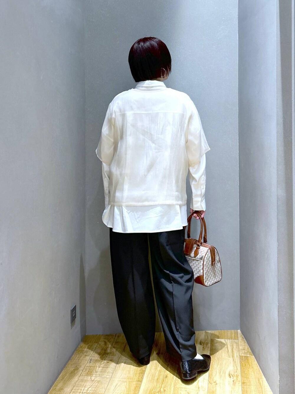 ブラック系のスラックス、ブラウン系のボストンバッグ、ブラック系のパンプスを着用したレディースの春コーディネートの5枚目の写真