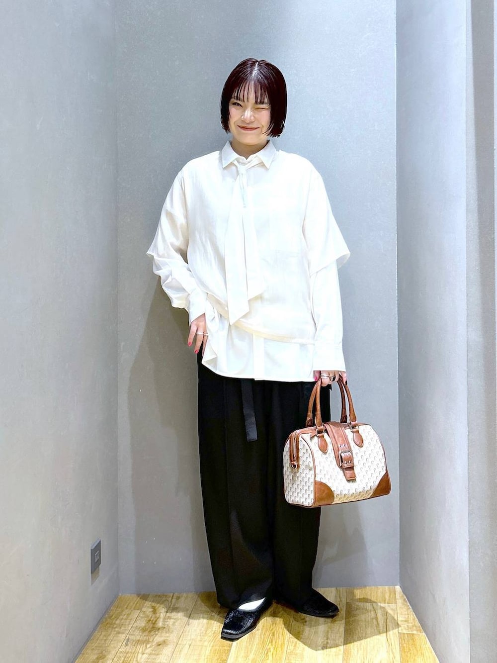 ブラック系のスラックス、ブラウン系のボストンバッグ、ブラック系のパンプスを着用したレディースの春コーディネートの2枚目の写真