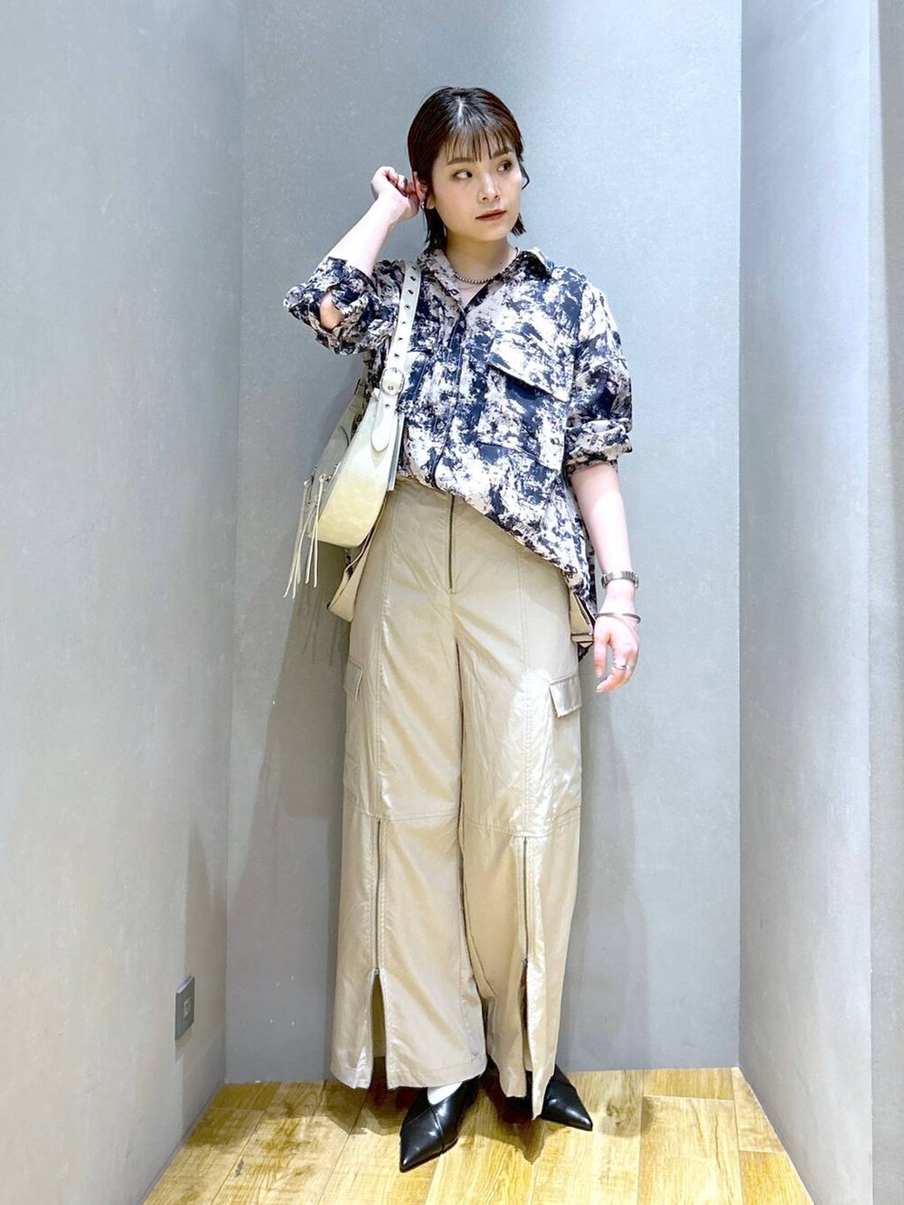 ホワイト系のショルダーバッグ、ブラック系のパンプス、ベージュ系のシャツ/ブラウスを着用したレディースの春コーディネートの2枚目の写真