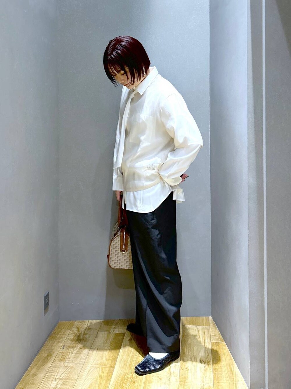 ブラック系のスラックス、ブラウン系のボストンバッグ、ブラック系のパンプスを着用したレディースの春コーディネートの4枚目の写真