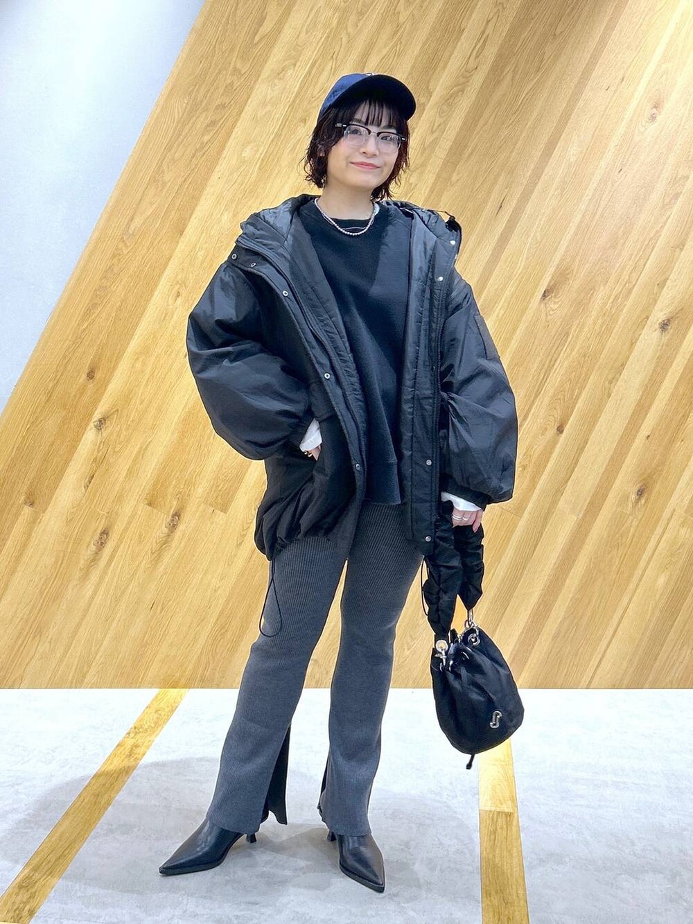 ブラック系のスウェット、ブラック系のブルゾン、ブラック系のハンドバッグを着用したレディースの冬コーディネートの2枚目の写真