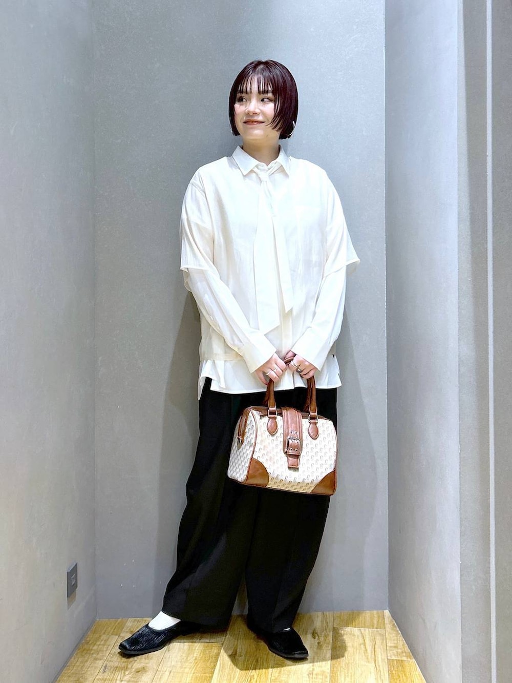 ブラック系のスラックス、ブラウン系のボストンバッグ、ブラック系のパンプスを着用したレディースの春コーディネートの3枚目の写真