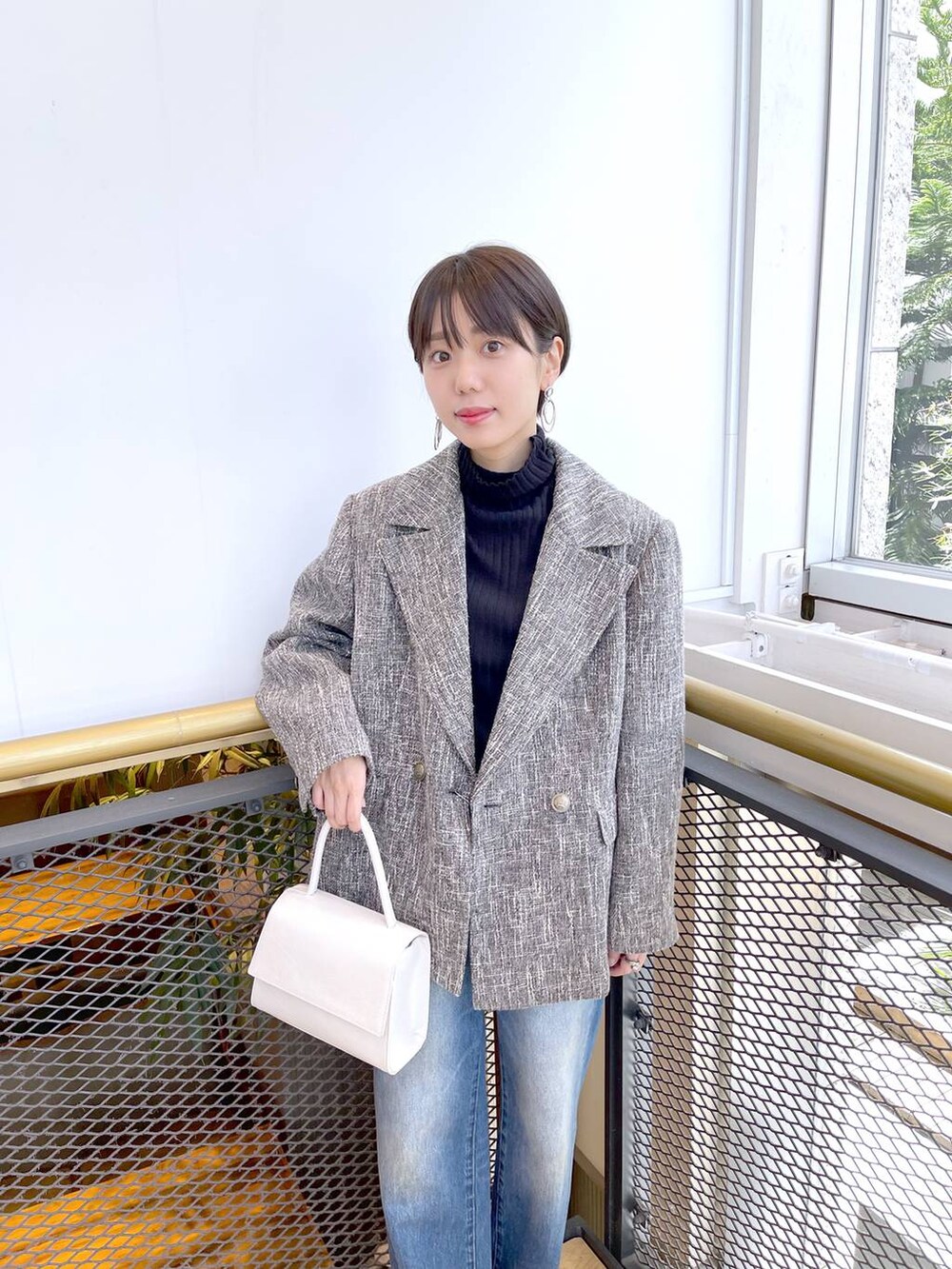 ホワイト系のハンドバッグ、ブラック系のブーツ、グレー系のテーラードジャケットを着用したレディースの秋コーディネートの2枚目の写真