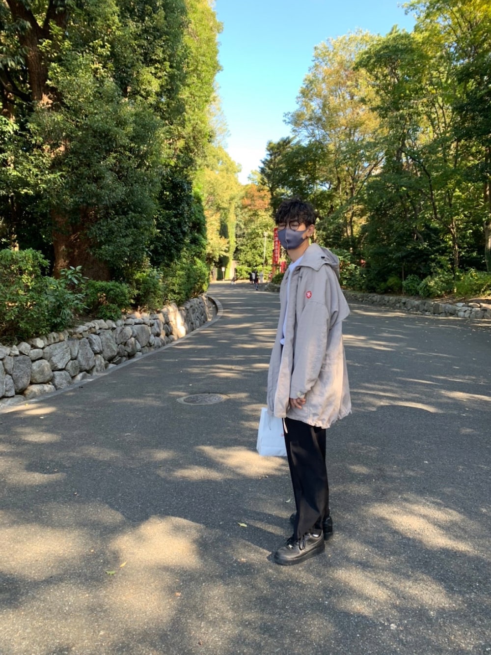 ブラック系のスニーカー、ベージュ系のマウンテンパーカー、ブラック系のスラックスを着用したメンズの秋コーディネートの2枚目の写真