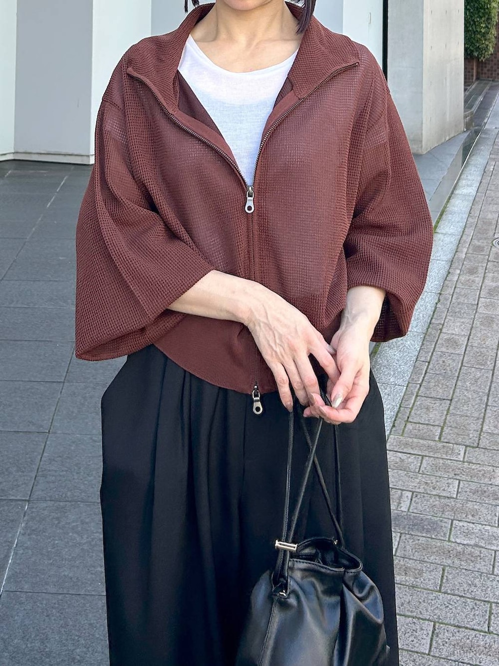 ブラック系のショルダーバッグ、レッド系のブルゾン、ブラック系のスラックスを着用したレディースの夏コーディネートの5枚目の写真